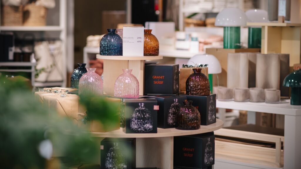 Display med dekorativa glasvaser, lampor och heminredningsprodukter presenterade i inredningsbutik.