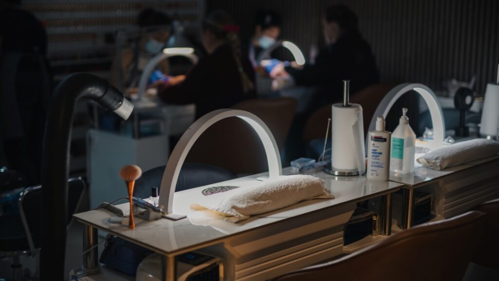 Manikyrstationer med UV-lampor, handdukar och nagelvårdsprodukter i nagelsalong.