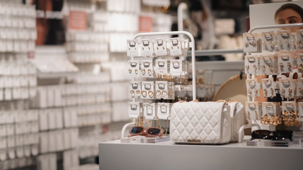 Display med smycken, örhängen, solglasögon och handväska uppställda i accessoarbutik.