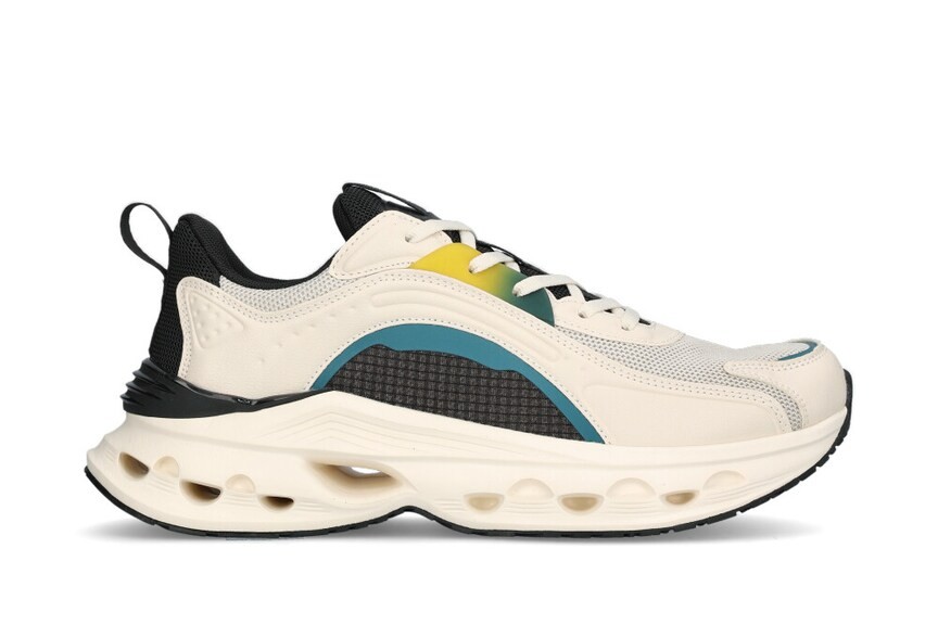 Beige och svart sneaker med färgdetaljer i blått och gult, tjock sula och snörning, visad från sidan mot vit bakgrund.